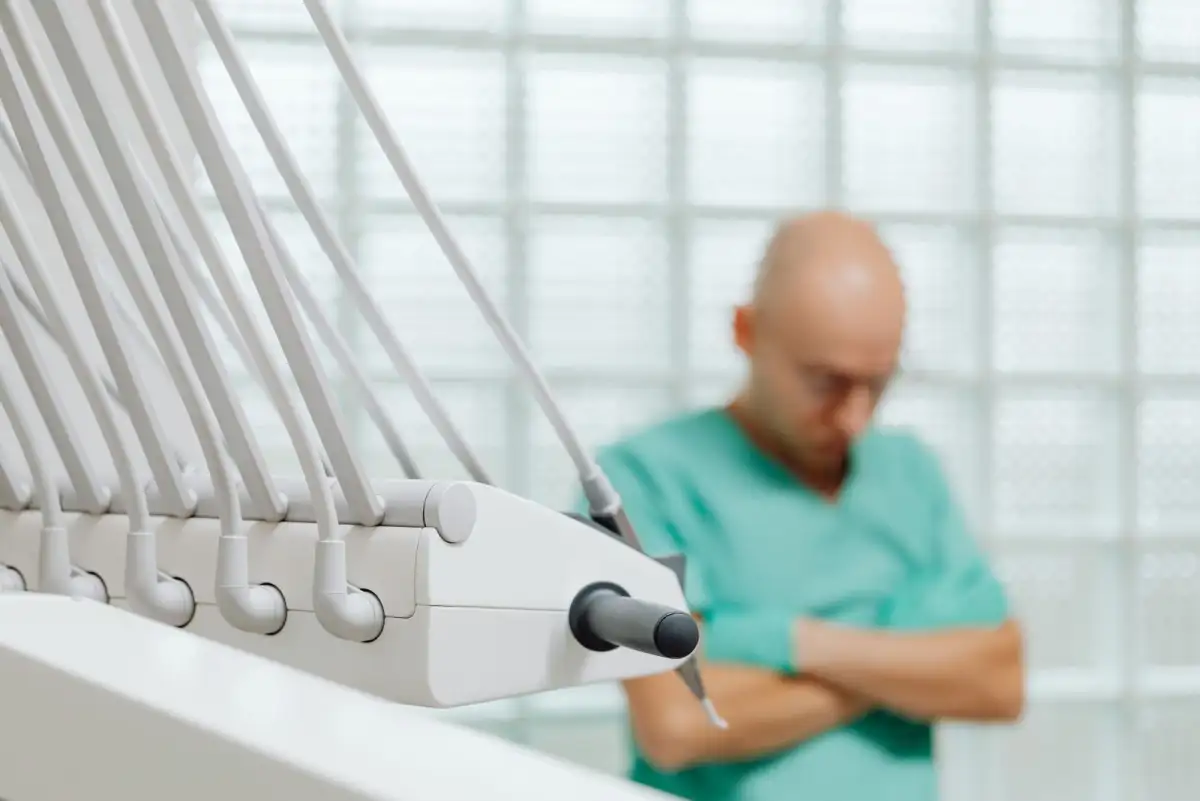 The instrument arm in the foreground, a dentist waiting between appointments