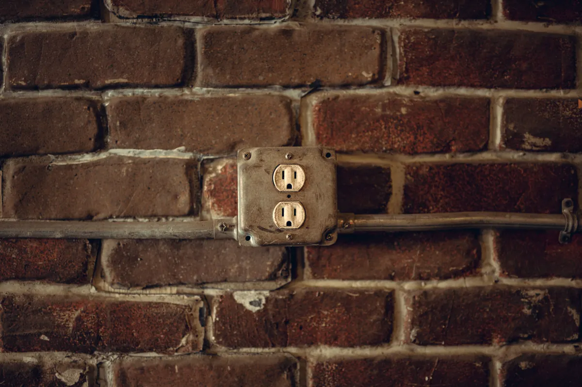 An old duplex receptacle set into a brick wall