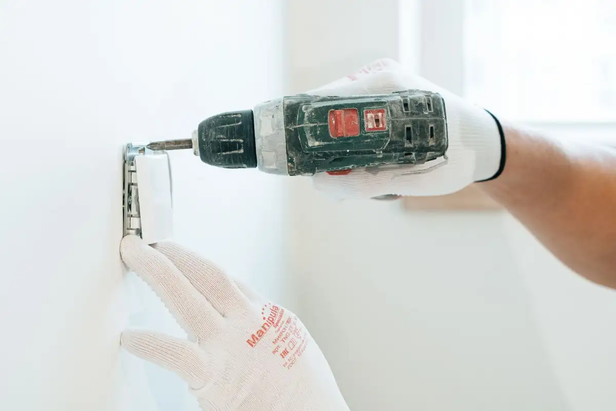 Gloved hands fitting a wall outlet