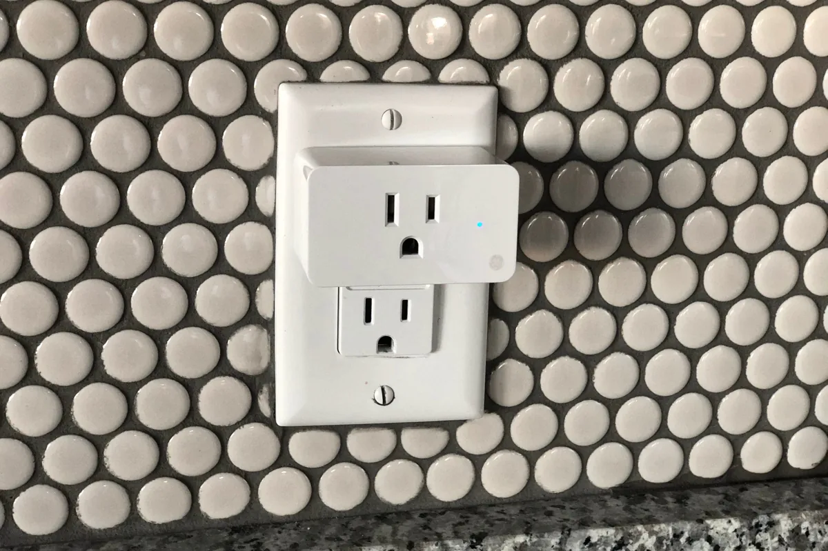 A duplex receptacle on a penny-tile wall
