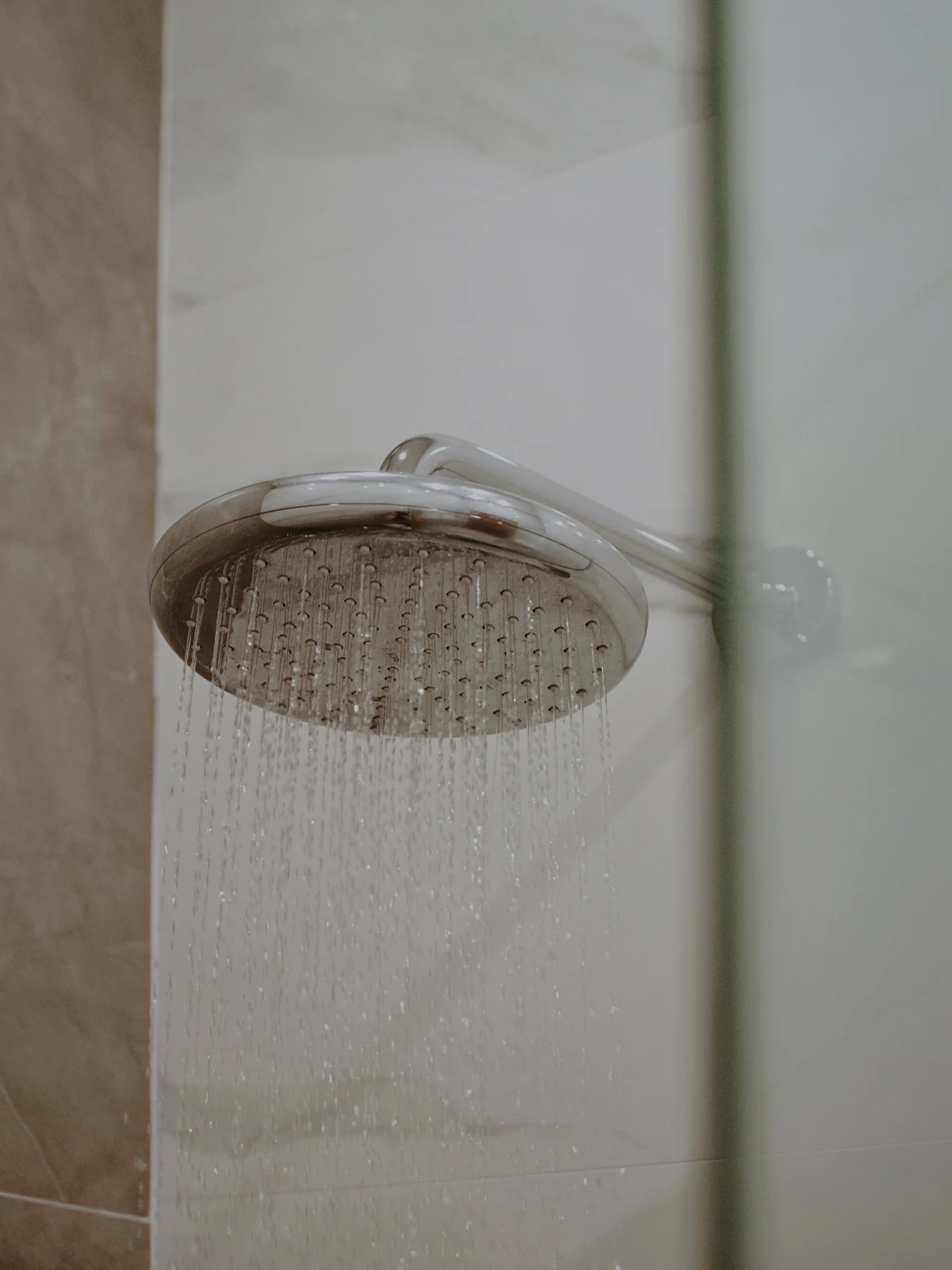 A rain shower head fixed to a tiled wall