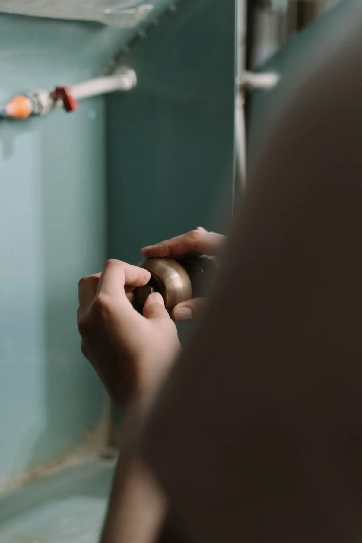 Hands working on a trap under a sink