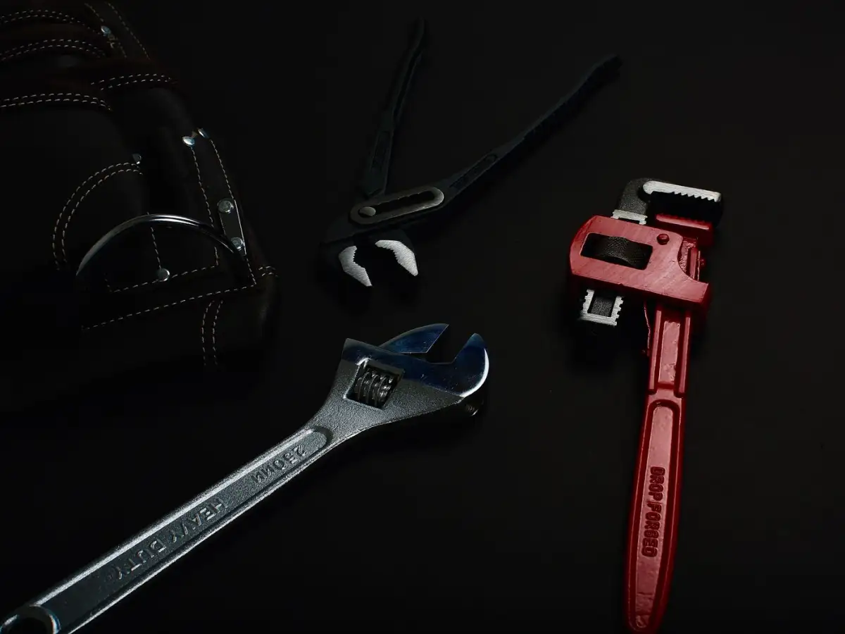 A pipe wrench on a dark bench