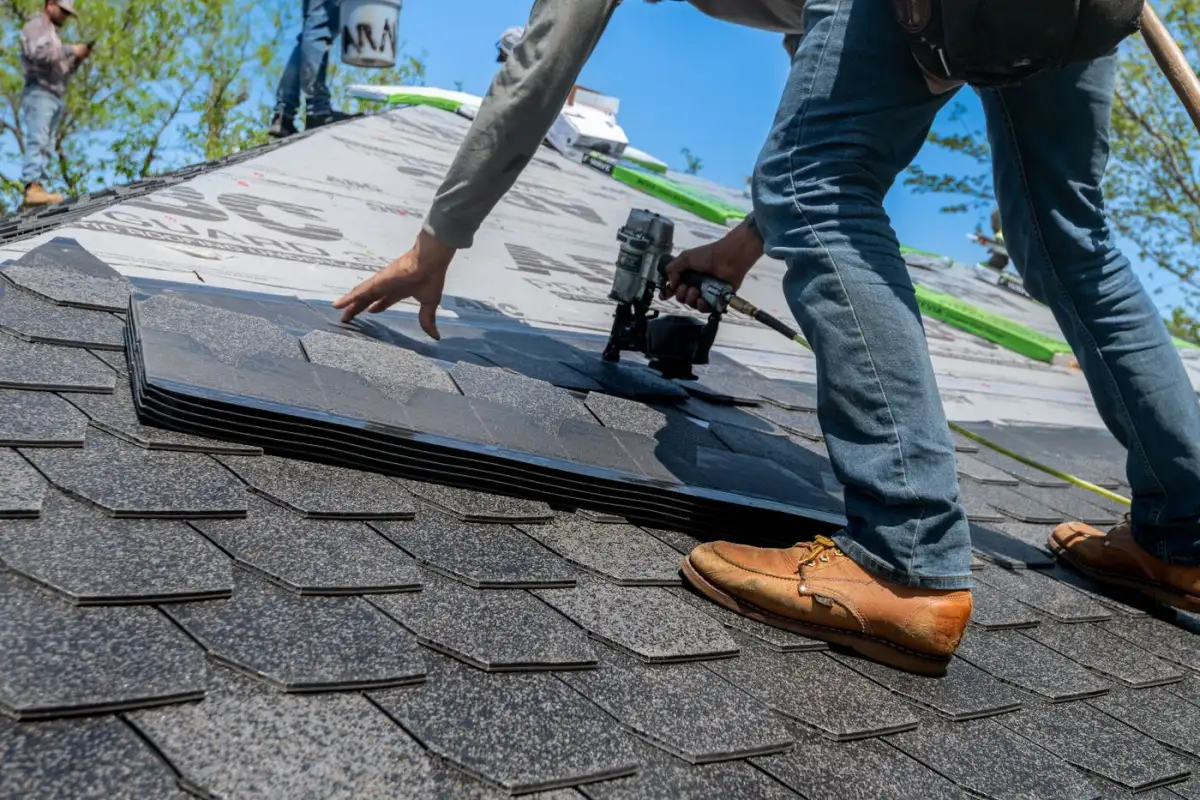 Asphalt shingles being laid and nailed down