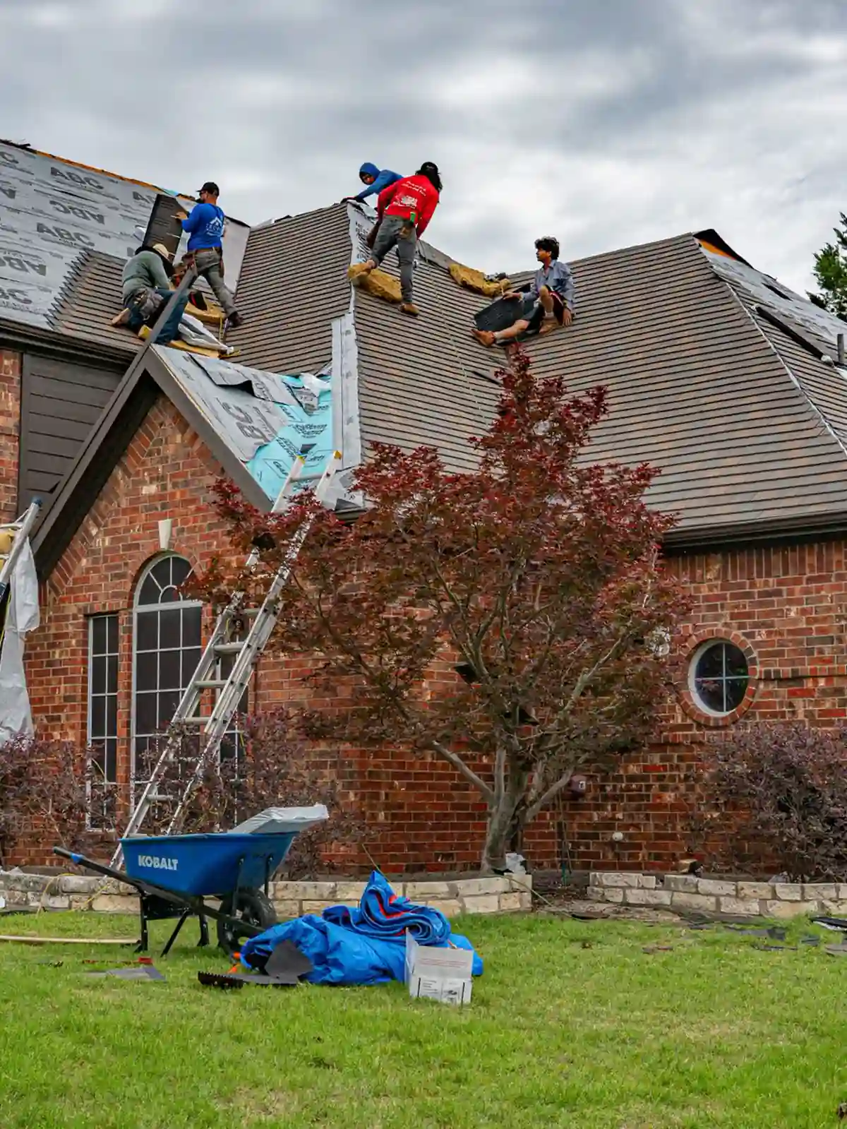 A ladder up to a brick house mid re-roof